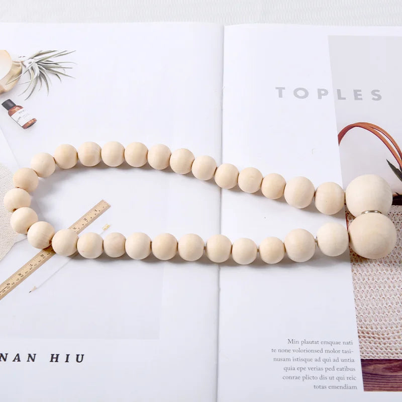 A necklace made of light beige wooden beads is displayed on a white background.