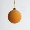 A round, golden-toned velvet flocked Christmas tree ornament hanging by a thin gold chain.