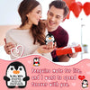 A couple holding a red gift box and a crochet penguin plush doll with a heart design.