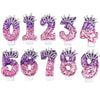 A set of glitter number birthday candle toppers in various colors and designs with rhinestone crowns.