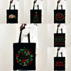 Black tote bag with a festive Christmas design featuring holly and greenery.