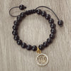 A black beaded bracelet with a gold charm featuring the zodiac symbol Virgo