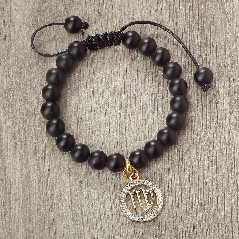 A black beaded bracelet with a gold charm featuring the zodiac symbol Virgo