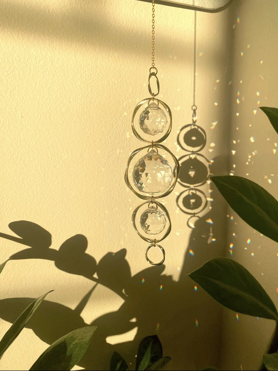 Suspension de cristaux soleil, décoration en verre clair suspendue par des chaînes, illuminée par la lumière du soleil.
