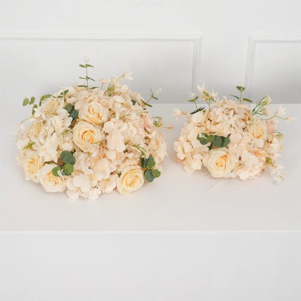 A bouquet of cream and pale yellow roses and hydrangea flowers arranged in a ball centerpiece.