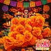 A large arrangement of bright orange artificial marigold flowers with stems used for Day of the Dead decorations.