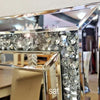 A silver crystal beveled wall mirror with a black frame and a glass shelf.