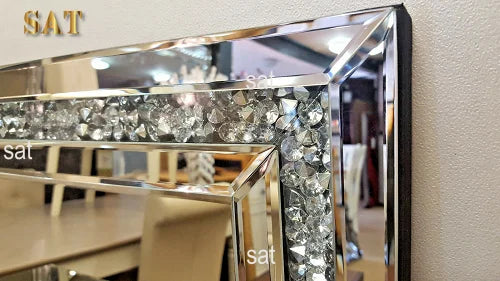 A silver crystal beveled wall mirror with a black frame and a glass shelf.