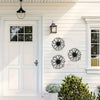 Black metal sunflower wall decor set mounted on white siding next to a white door and window