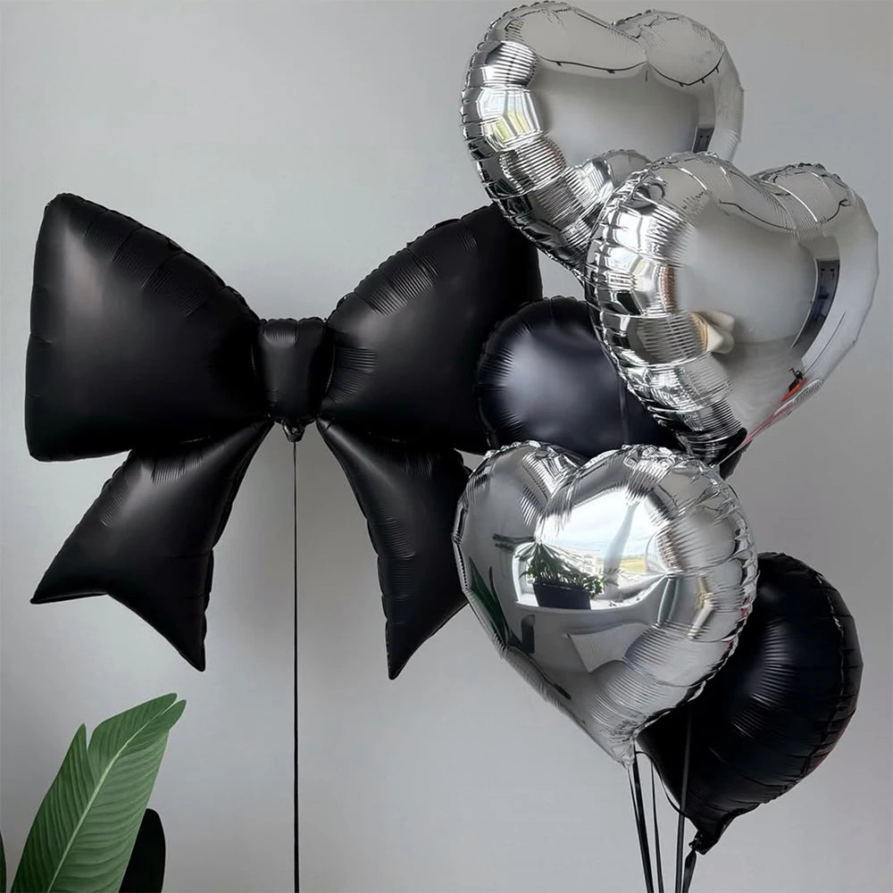 A collection of black and silver heart-shaped foil balloons, including a large bow and several hearts.