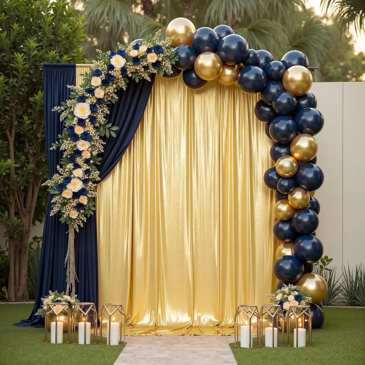 A golden sequin backdrop curtain decorated with blue and gold balloons and floral greenery for an event.