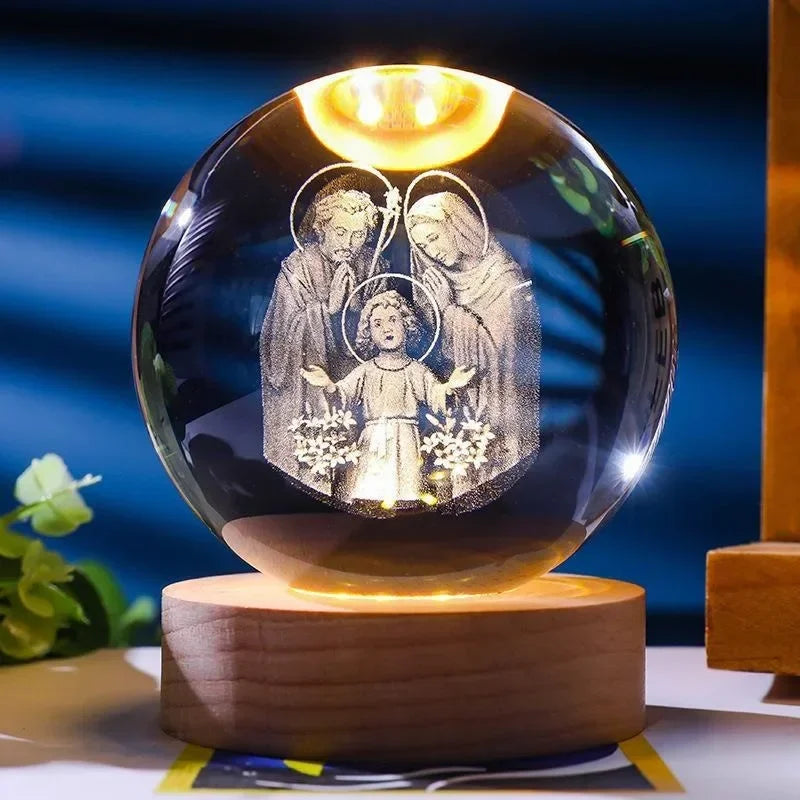 A spherical crystal ball night light featuring a depiction of two figures with halos on a wooden base.