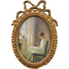 A vintage gold-toned bowknot picture frame with an oval frame, displaying a portrait of a woman.