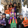 A group of people dressed in Halloween costumes holding orange and black treat bags with pumpkin and ghost designs.