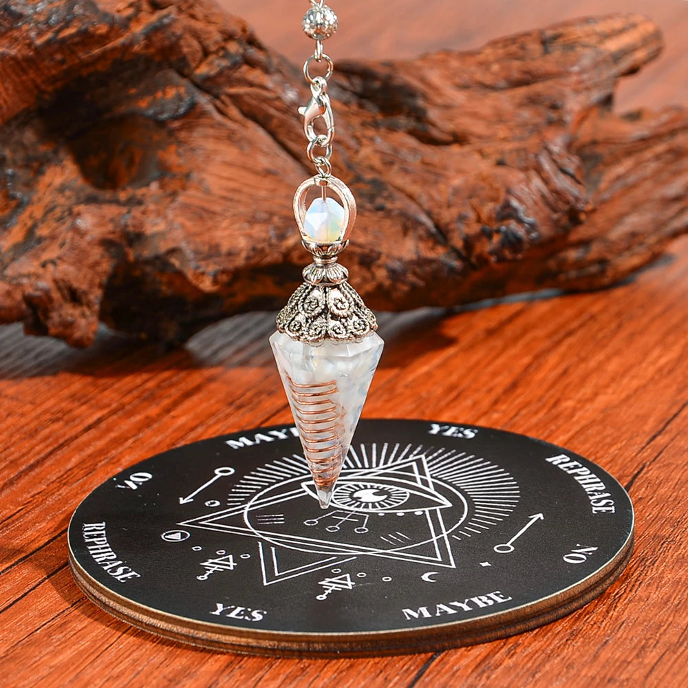 A crystal pendulum set featuring a clear quartz point mounted on an ornate silver chain and resting on a wooden divination bo