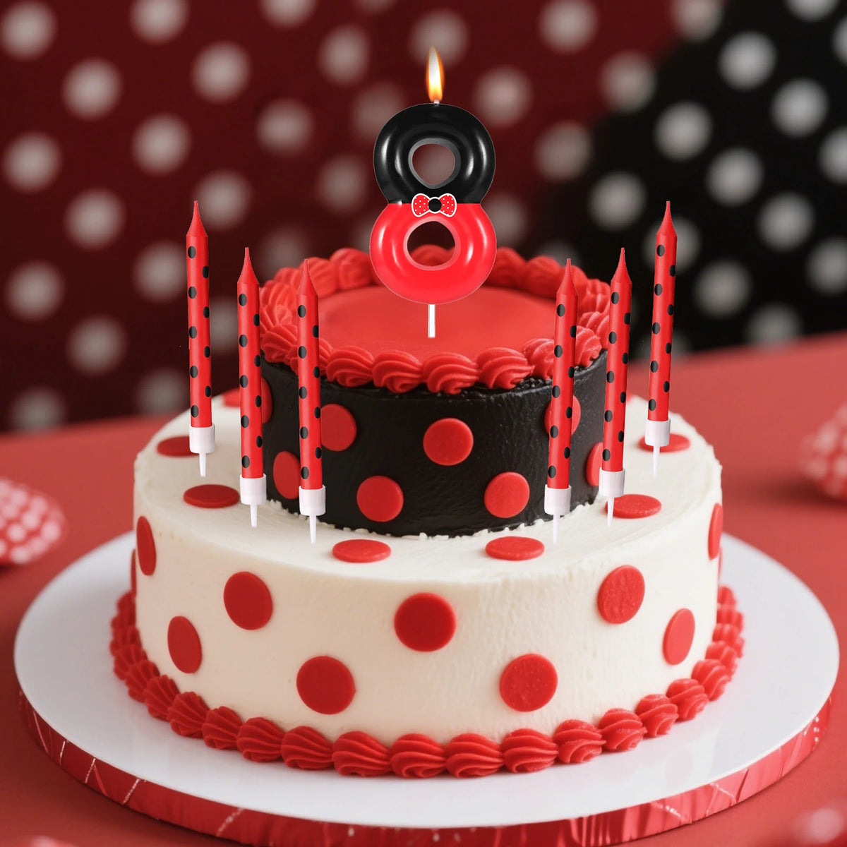 A birthday cake decorated with red and black polka dots, topped with a red candle shaped like the number zero.