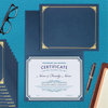 A stack of dark blue certificate holders with gold foil frames rests on a teal textured surface.