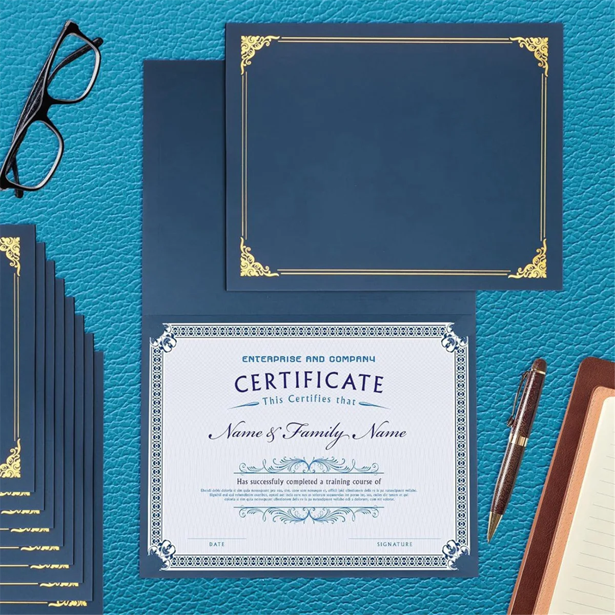 A stack of dark blue certificate holders with gold foil frames rests on a teal textured surface.