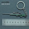 A miniature green alloy gun model keychain with a metal split ring attached, shown next to a ruler.
