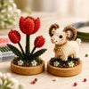 A craft kit featuring red and green glass beads arranged in floral shapes, including a white animal figure.
