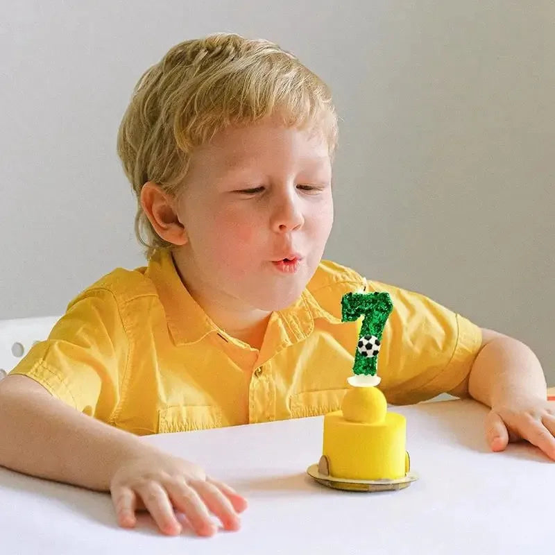 A young child is looking at a yellow birthday candle shaped like the number seven on a white table.