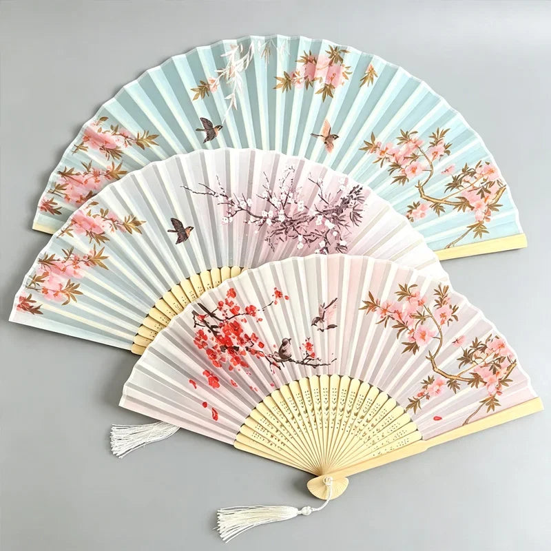 A set of elegant floral bird print bamboo folding fans in pale blue and pink tones.