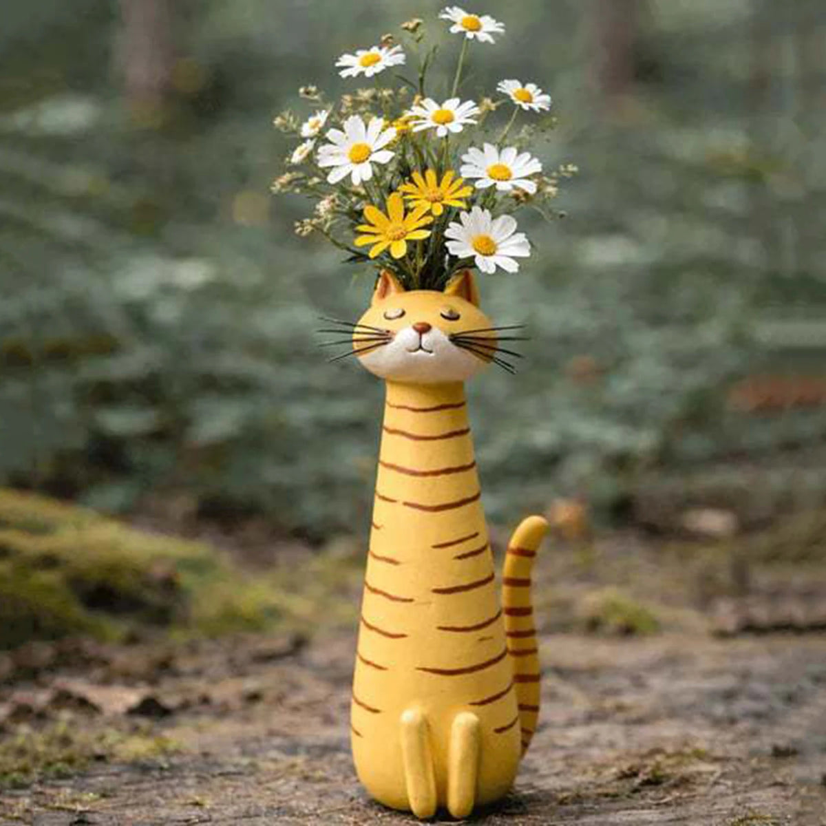 A yellow resin cat figurine with a flower vase on its head, set in a natural outdoor environment.