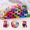 A collection of colorful satin balloon ribbon rolls in various shades and colors arranged on a white surface.