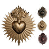 A brass wall plaque featuring a radiant sunburst design surrounding a heart motif.