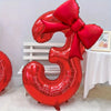 A large red foil number balloon shaped like the number 3, tied with a matching red bow.