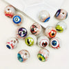 A collection of glossy, double-sided eyeball beads in various colors and patterns for crafting.