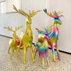 A set of two foil balloons shaped like deer, colored in gold and iridescent rainbow hues.
