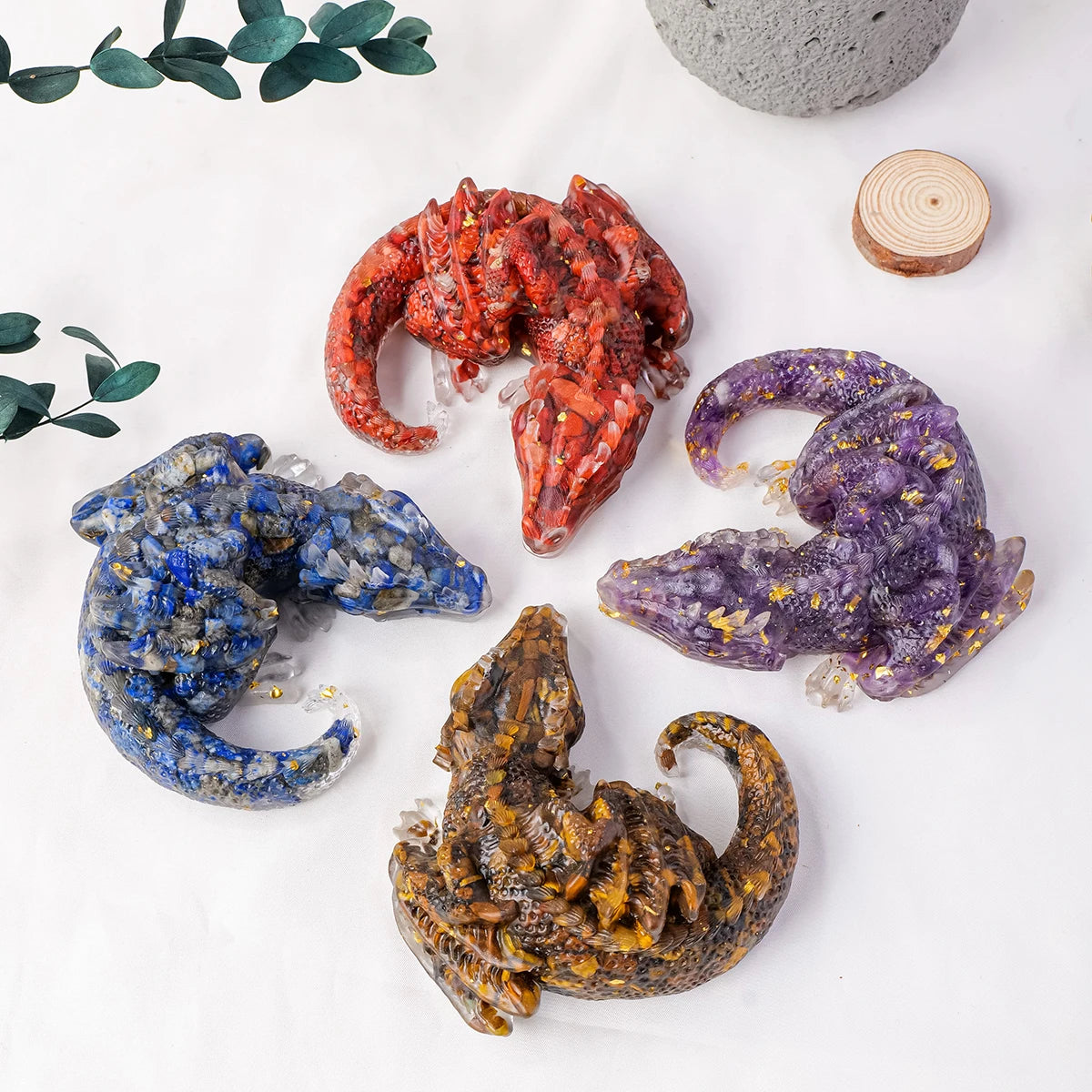 A collection of natural crystal dragon figurines in various colors including red purple blue and gold on a white background.