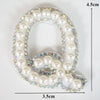 A white pearl letter Q rhinestone patch for clothing with iridescent accents.