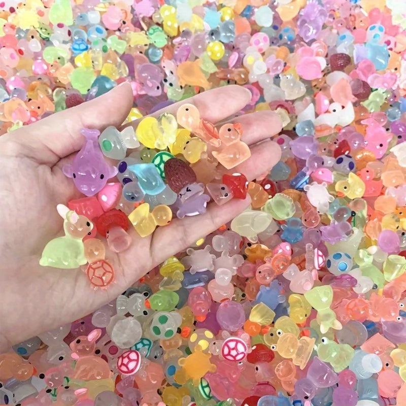 A hand holds a large quantity of colorful luminous resin animal figurines for aquarium decor.