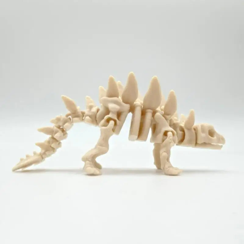 A light beige 3D printed dinosaur skeleton model for desktop display.