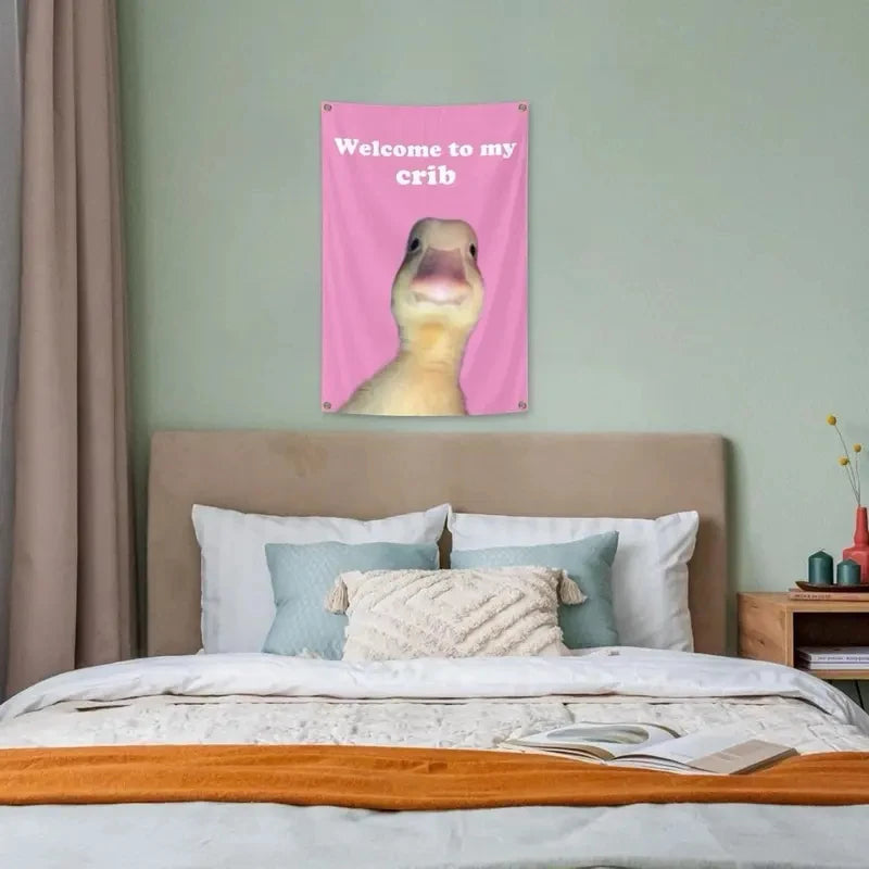 A pink wall tapestry featuring a cartoon duck welcoming someone to its crib.