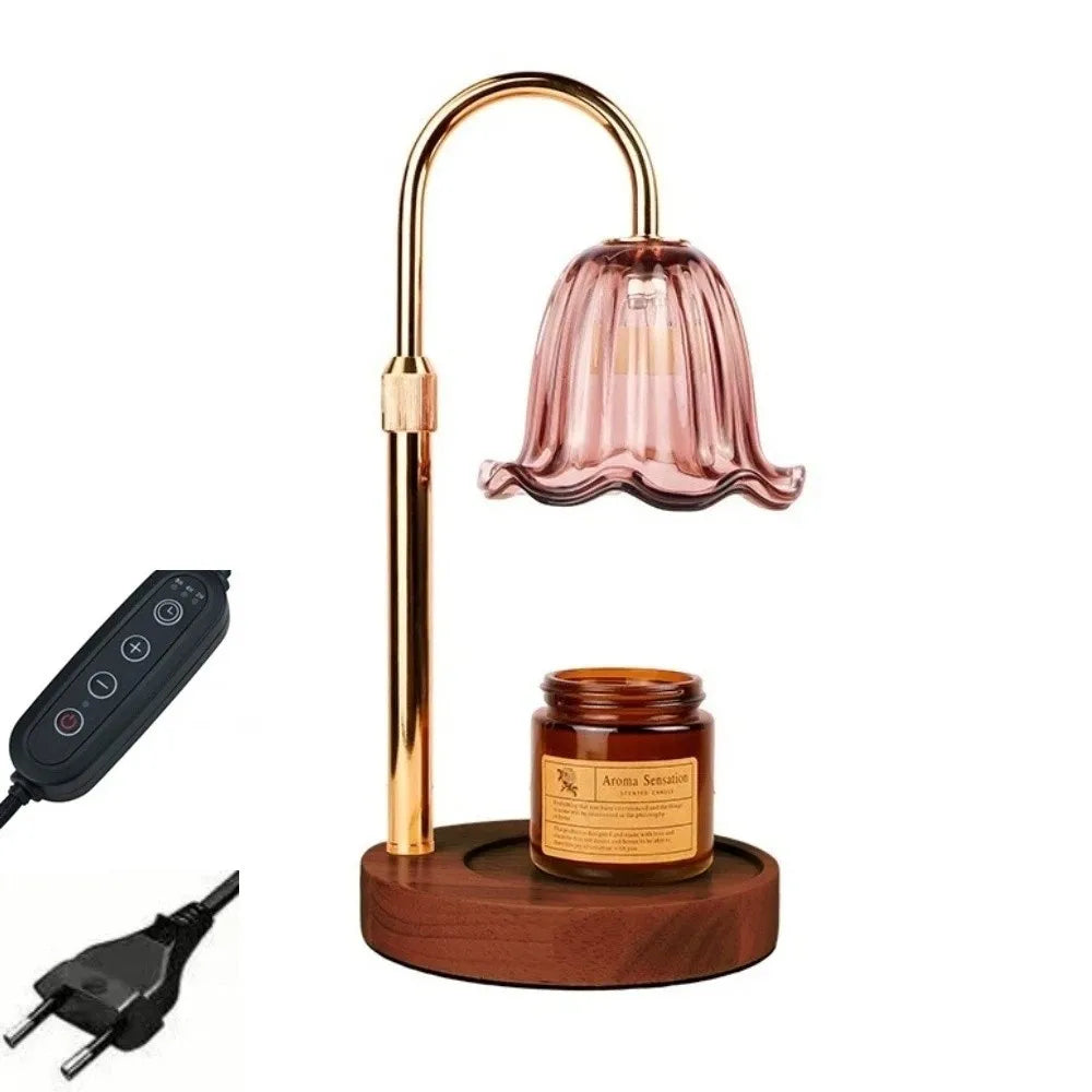 A gold-toned adjustable height aromatherapy candle warmer lamp with a pink glass shade and a wooden base.
