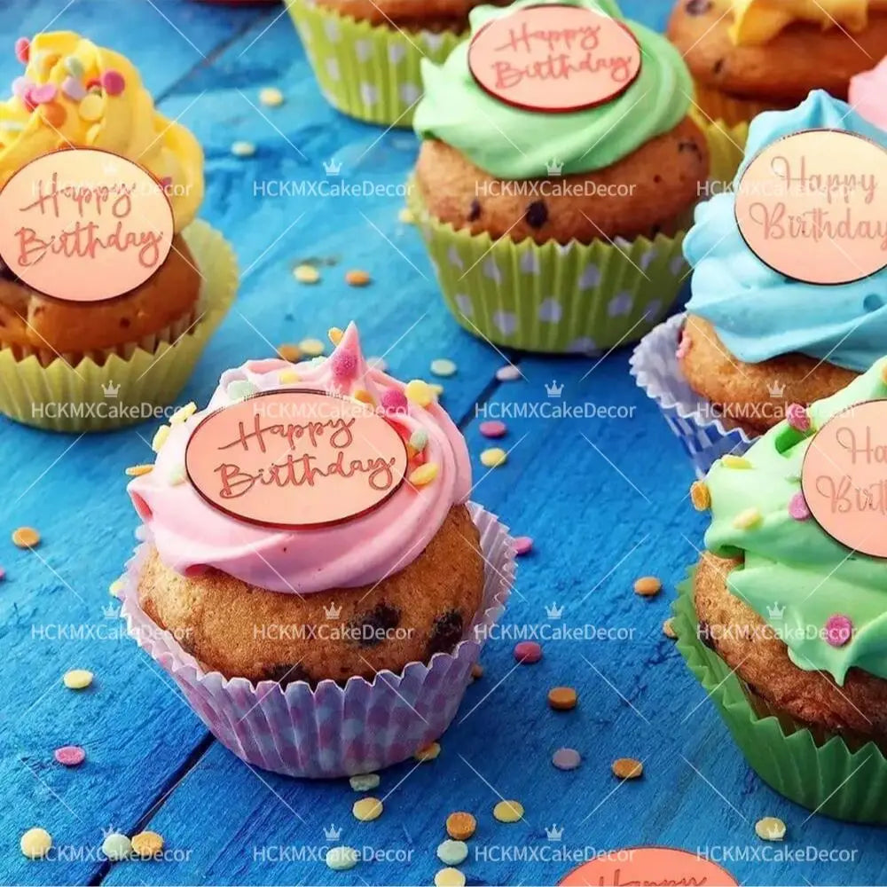 A collection of colorful cupcakes decorated with happy birthday toppers in various shades of green, pink, and blue.