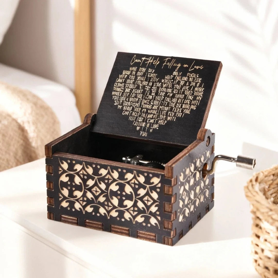 A dark wood music box with an engraved melody is displayed on a white surface.