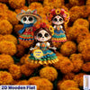Two flat wooden skull ornaments with colorful floral decorations set against a background of orange flowers.