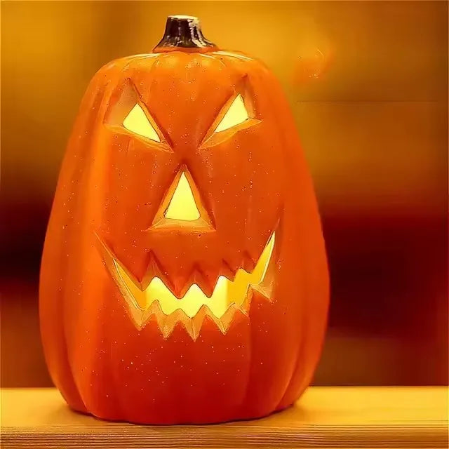 An orange glowing Halloween pumpkin lantern with carved facial features sitting on a wooden surface.