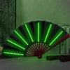 A folding LED fan with green lights is displayed against a green wall.