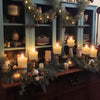 A display of glowing candles and greenery on a dark wooden cabinet.