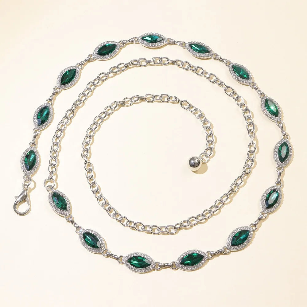 A delicate silver waist chain featuring emerald green crystals and small diamonds.
