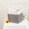 A gray fabric storage cube with a white rim holds a small stuffed animal.