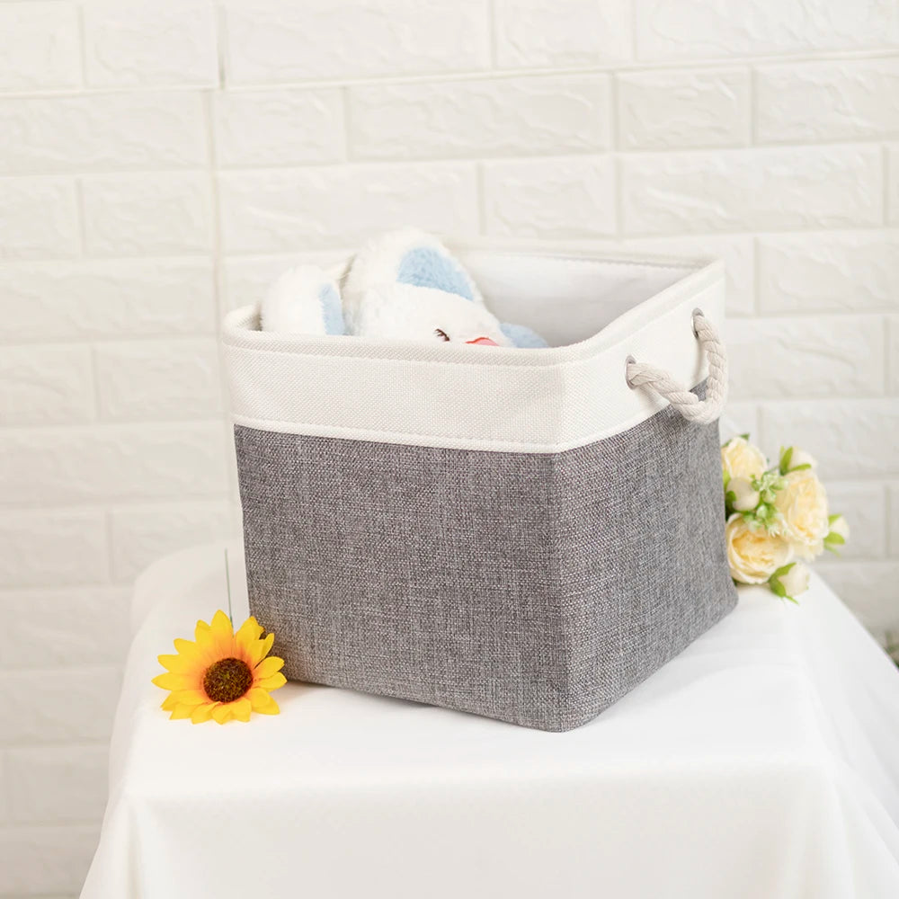 A gray fabric storage cube with a white rim holds a small stuffed animal.