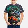 A young boy wearing a black t-shirt featuring a full graphic print of Monster Jam vehicles like Grave Digger and a race car.