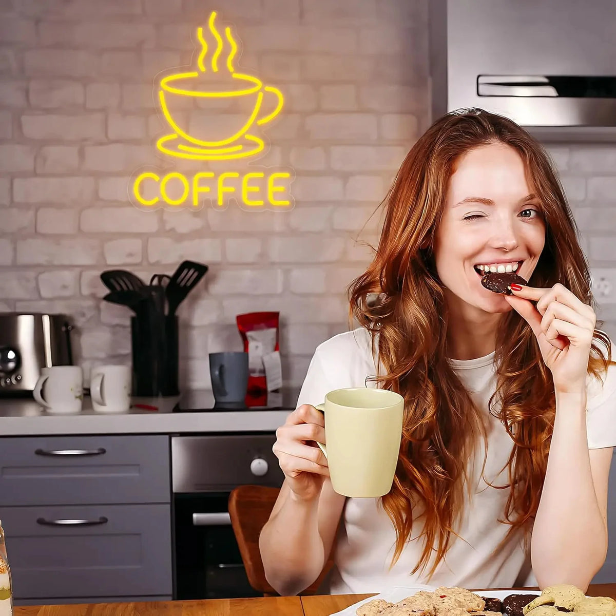 A smiling woman holds a mug of coffee in front of a brick wall sign that reads COFFEE