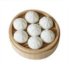 A set of white steamer buns and dumplings arranged in a wooden tray for fridge magnets.